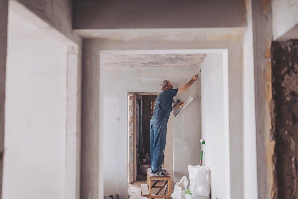 Bauarbeiter auf der Baustelle erneuert Gips von Innenwänden und Decken mit Schwimmer und Gips.